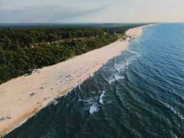Malowniczy klif w Jastrzębiej Górze z widokiem na piaszczystą plażę i Bałtyk.